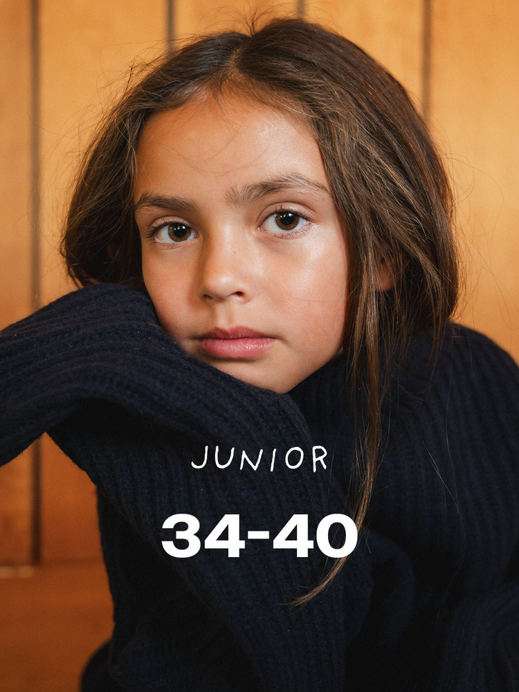An older child in a navy ribbed jumper leaning on her arm